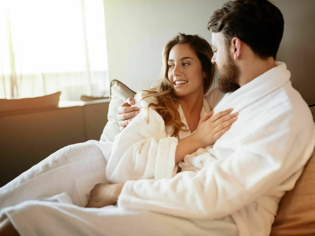 Couple sit in spa robes with warm lighting