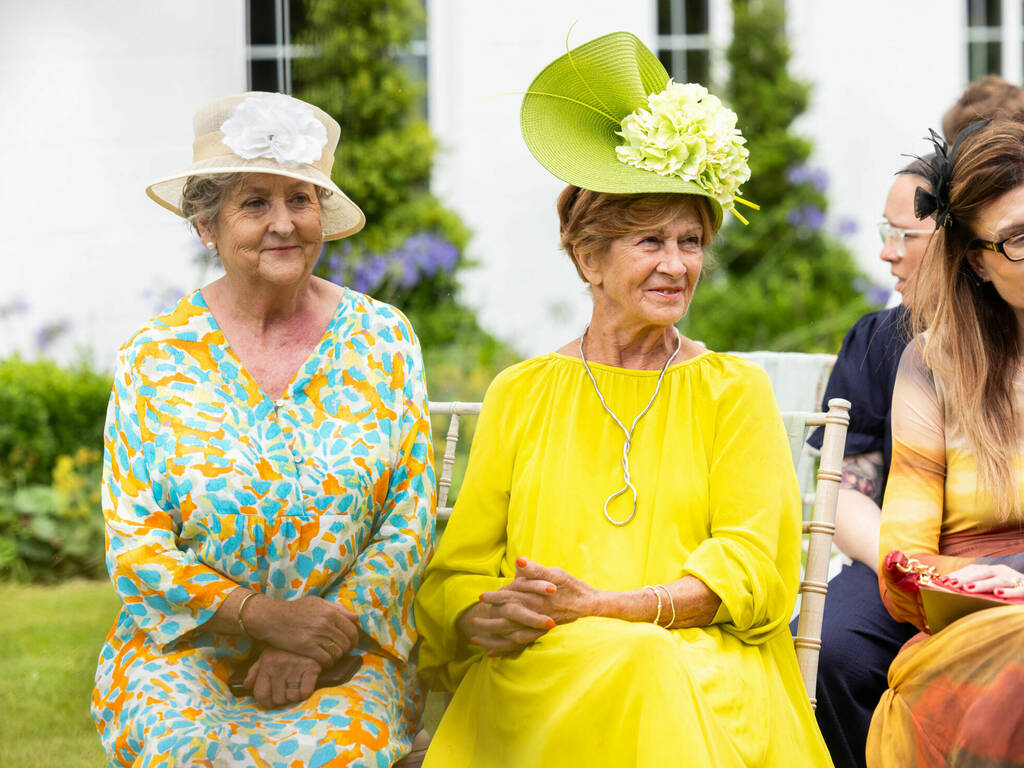 Colourful wedding guests during an outdoor wedding ceremony at Rowton Hall Hotel