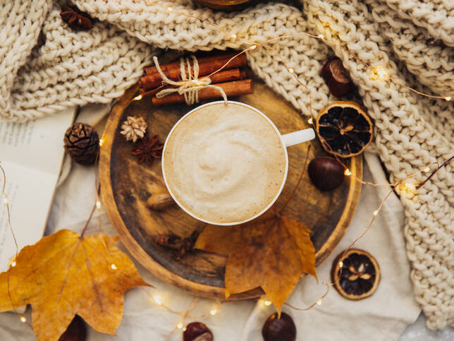 Autumnal image of hot drink and autumn leaves with blanket