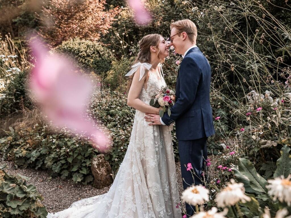 Bride and groom framed with flowers in walled garden at Rowton hall hotel