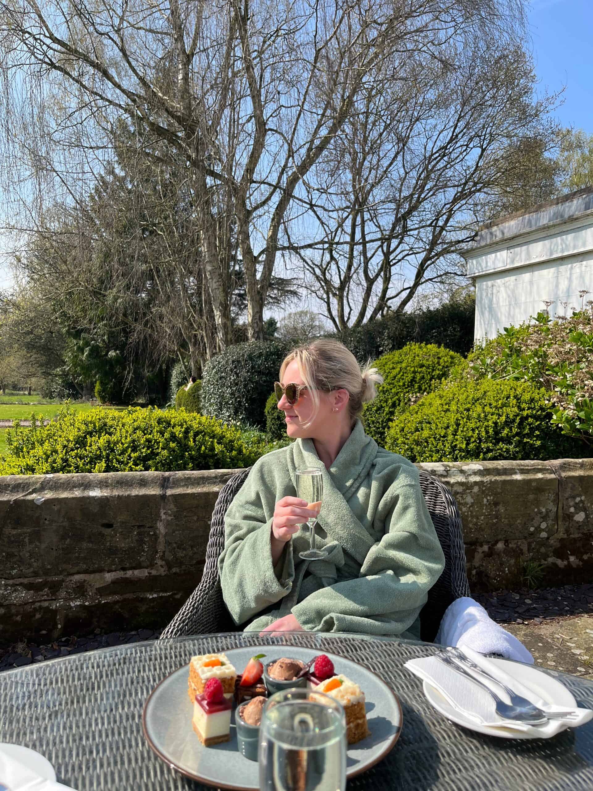 Woman enjoys a spring spa day - Sip, spa, sweet retreat treat plate and fizz on the patio at rowton hall hotel, luxury spa chester
